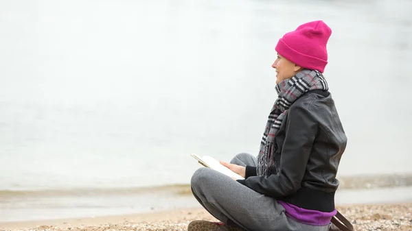 海の近くの若い女性の読書本 — ストック写真