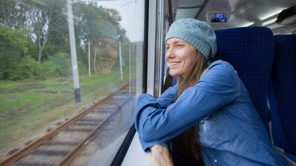 漂亮的姑娘乘火车旅行 用电话从窗户向外张望 — 图库照片