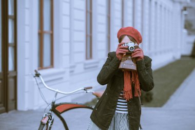 Sokakta retro kameralı ve bisikletli genç bir kadın.