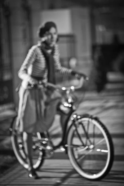 Blurred image of woman on the bike, retro, skirt, street. Girl on bike, enjoy sunny autumn or spring day