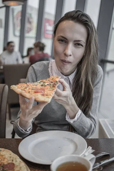 Beautiful woman eating pizza in a cafe