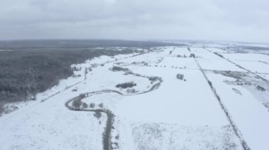 bir dron yukarıda bir forest yakınındaki dar bir sarma nehir üzerinde bir karlı kış bulutlu günde uçuş