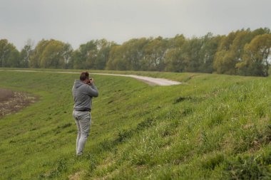 Kamerayla fotoğraf çeken ve geniş bir alanı keşfeden adam.
