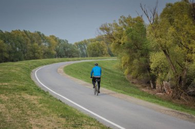 Bisikletli adam bisiklet egzersizi yapıyor, kırsal alanda.