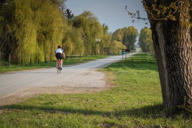 Bisikletli adam bisiklet egzersizi yapıyor, kırsal alanda.
