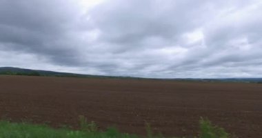 Arka planda dağlar ve karanlık gökyüzü ile alanın yanında araba sürüş.