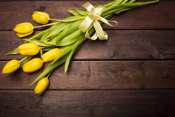 Spring card: yellow tulips on a dark wooden background. Top view, lay flat — Stock Photo, Image