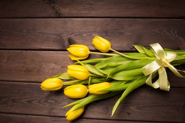 Spring card: yellow tulips on a dark wooden background. Top view, lay flat — Stock Photo, Image