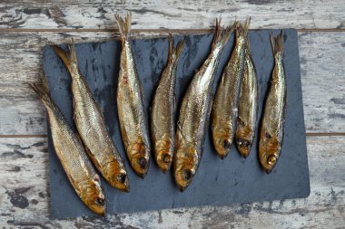 Tahta bir masa ve tahtada tütsülenmiş ringa balığı..