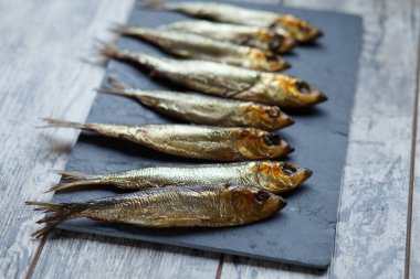 Tahta bir masa ve tahtada tütsülenmiş ringa balığı..