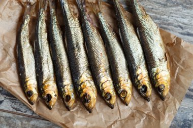 Kağıt üzerinde tütsülenmiş ringa balığı ve ahşap masa.