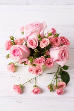 Pembe gül çiçek beyaz ahşap zemin üzerinde. Çiçekli natürmort. Seçici odak. 