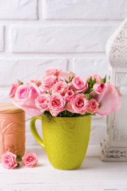 Pembe gül çiçek beyaz duvara karşı yeşil Kupası. Çiçekli natürmort. Seçici odak. Dikey görüntü.