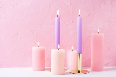 Pembe ve mor pembe dokulu duvar tarafından yakınındaki mumlar yanan. Metin için yer. Seçici odak.