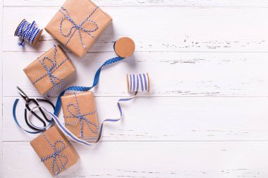 Sarılmış hediye kutuları ile sunar, makas, mavi şerit ve üzerinde ahşap dokulu arka plan etiketleri. Seçici odak. Metin için yer. Düz yatıyordu.