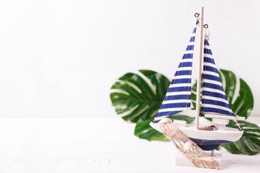 Dekoratif ahşap oyuncak tekne ve tropikal bitki dokulu beyaz zemin üzerine bırakır. Metin için yer. Yaz, tatil kavramı.