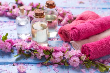 Temel aroma yağı, çiçek ve havlu mavi ahşap zemin üzerinde. Seçici odak. Spa kavramı. Organik kozmetik.