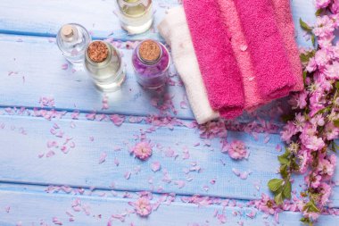 Temel aroma yağı, çiçek ve ahşap arka plan mavi pembe havlu. Seçici odak. Spa kavramı. Organik kozmetik. Yukarıdan görüntülemek.