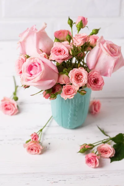 粉红色的玫瑰花在蓝色杯子对白色墙壁 花静物 选择性对焦 垂直图像 — 图库照片