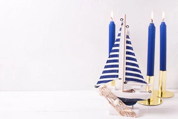 Dekoratives Holzspielzeugboot Und Blaue Brennende Kerzen Auf Weißem Strukturiertem Hintergrund — Stockfoto
