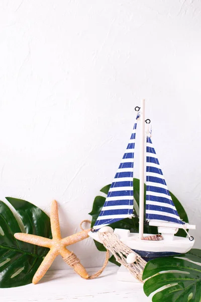 ホワイト テクスチャ背景に装飾的な木製おもちゃのボート 海の星 熱帯植物を残します テキストを配置します 垂直方向の画像 休暇の概念 — ストック写真