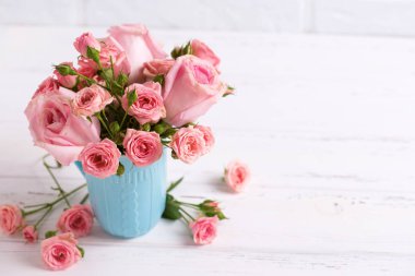 Pembe gül çiçek beyaz duvara karşı mavi Kupası. Çiçekli natürmort. Seçici odak. Metin için yer.