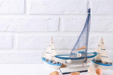 Okyanus yaşam süslemeleri. Dekoratif tekneler ve beyaz tuğla duvar tarafından yakınındaki kabukları. Seçici odak. Metin için yer.