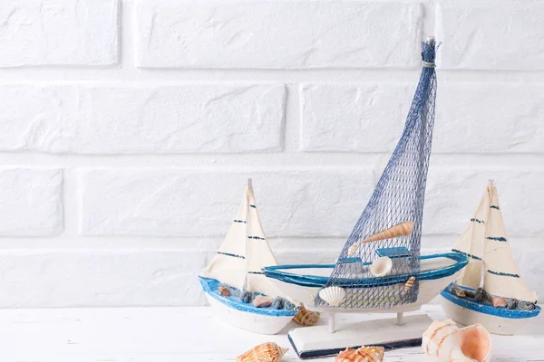 Okyanus yaşam süslemeleri. Dekoratif tekneler ve beyaz tuğla duvar tarafından yakınındaki kabukları. Seçici odak. Metin için yer.
