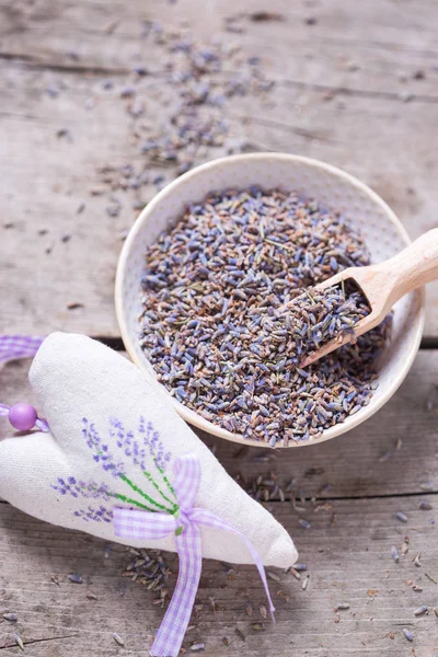 Dry lavender buds bowl  and sachet with lavender on vintage wooden background. Selective focus. Vertical image.