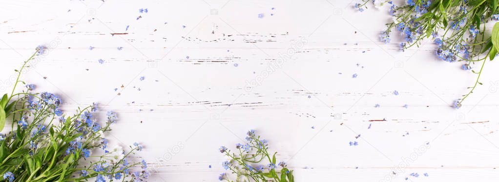 Frame from  blue forget-me-nots or myosotis flowers on  white wooden background. Floral still life. Selective focus. Place for text. View from above.