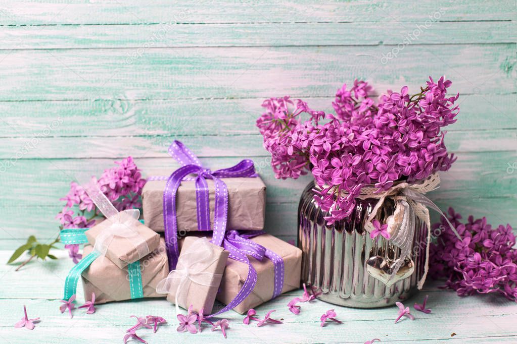 Aromatic  lilac flowers in vase and boxes with gifts on turquoise background. Selective focus. Place for text.