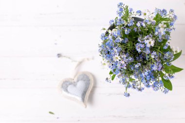 Çerçeve mavi korun veya myosotis çiçek ve kalp Beyaz ahşap zemin üzerinde 