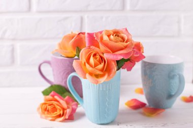 Taze turuncu gül beyaz tuğla duvar zemin üzerine mavi Kupası