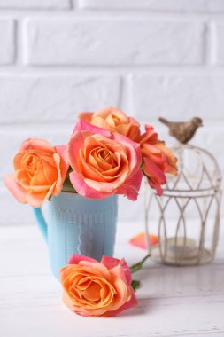Mavi Kupası ve tuğla duvara Beyaz ahşap zemin üzerinde mum taze turuncu gül