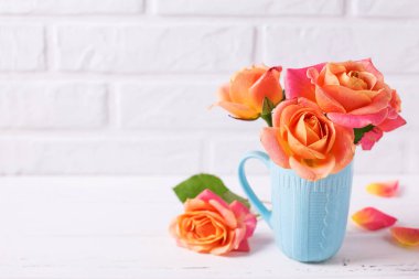 Taze turuncu gül beyaz tuğla duvar zemin üzerine mavi Kupası