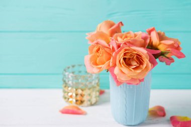 Turkuaz duvar zemin üzerine mavi Kupası'nda taze turuncu gül demet