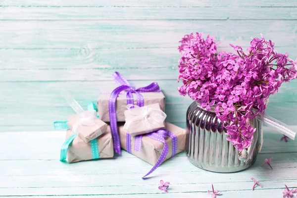 Purple lilac flowers and boxes with presents on turquoise background