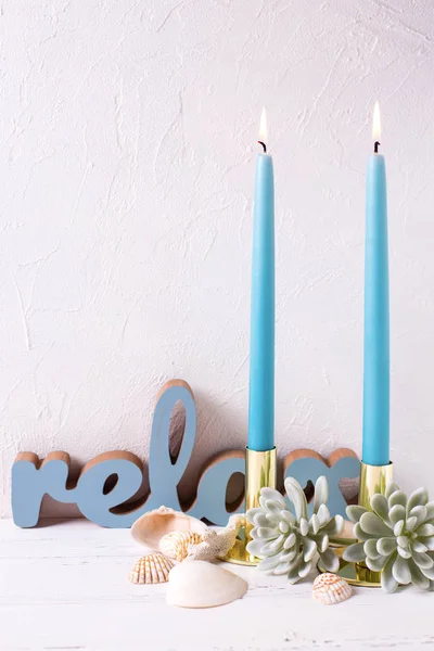 Marine decorations and two blue burning candles on white textured background