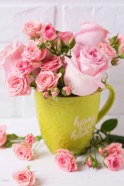 粉红色玫瑰花在绿色杯子反对白色砖墙 — 图库照片