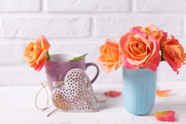 ブルーのカップと白い壁に白い木製の背景に装飾的な心に新鮮な明るいバラ — ストック写真