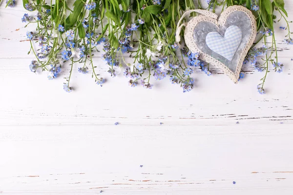 Çerçeve mavi korun veya myosotis çiçek ve kalp Beyaz ahşap zemin üzerinde 