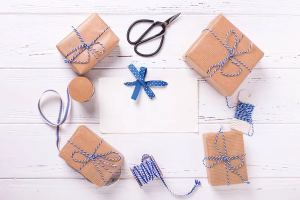 空标签和包装礼品盒与礼物和蓝色丝带在纹理的木质背景 — 图库照片