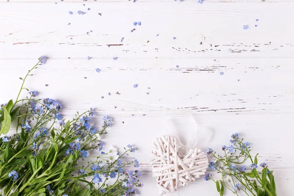 Çerçeve mavi korun veya myosotis çiçek ve kalp Beyaz ahşap zemin üzerinde 