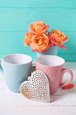 İki bardak ve turkuaz duvara turuncu gül. 