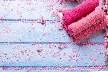 Pembe banyo havlusu mavi ahşap arka plan üzerinde kümesi.
