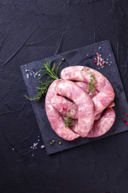 Otlar ve baharatlar siyah arka plan üzerine çiğ sosis