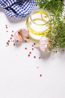 Şişe zeytinyağı otlar ve baharatlar üzerinde beyaz dokulu arka plan ile. Üstten görünüm. Seçici odak. Metin için yer. Dikey görüntü.