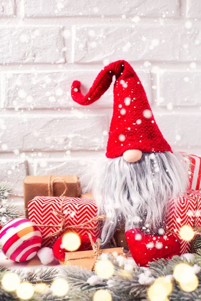 Winter holidays  decorations. Funny elf, wrapped christmas presents, balls,  fir tree branches on white textured  background. Selective focus