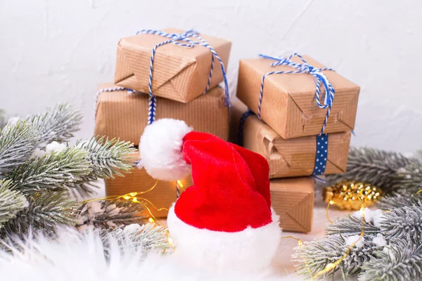 Red Santa kalap, csomagolt dobozok ajándékokkal, fenyőfa ágak egy — Stock Fotó