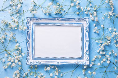 Mavi boş vintage çerçeve ve taze beyaz alçı çiçek